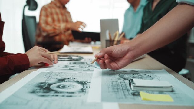 Team members engage in collaborative discussions while examining technical drawings in a modern office space, emphasizing creativity, communication, and teamwork. SACTR