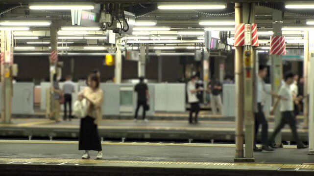 TOKYO, JAPAN - JUL 2025 : Crowded train station in Tokyo. Commuters, people and traffic during rush hour. Daily urban life, business, and public transportation in a busy metropolis. Time lapse shot.