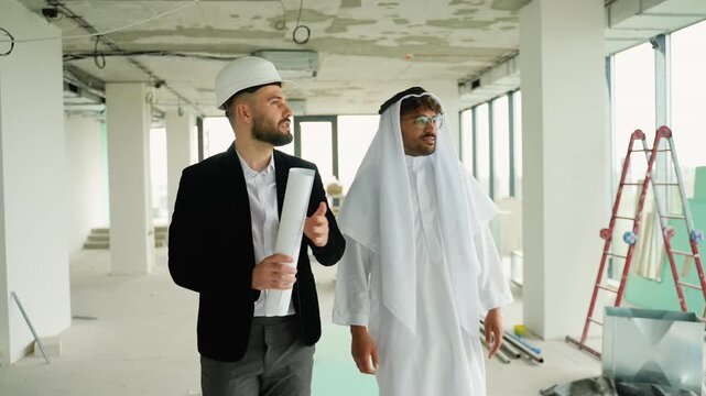 Architect showing construction plans to Arab investor in building under construction