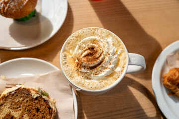 Hot pumpkin spice latte cup topped with whipped cream and slice of cake on a cafe table, cozy, autumn atmosphere. High quality photo