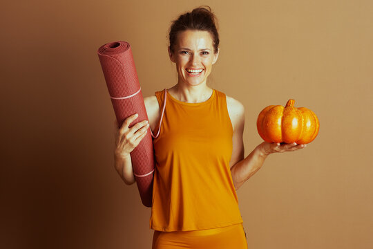 Smiling Woman with Yoga Mat and Autumn Pumpkin
