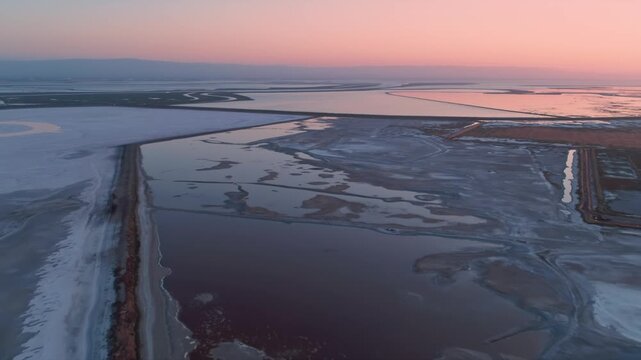 Aerial view of San Francisco Bay Salt Ponds, Fremont, California, USA, at sunset. The ponds are used for salt production, and the different colors indicate varying salinity levels.