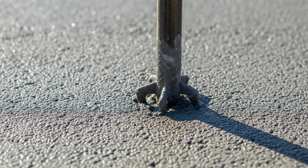 Obraz premium Industrial machine tool creating textured grooved surface on fresh concrete for enhanced traction and safety in construction projects, close up detail of paving process