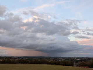 Storm cloud rolling over rural landscape in England at sunset, thunderstorm summer time dramatic skies 