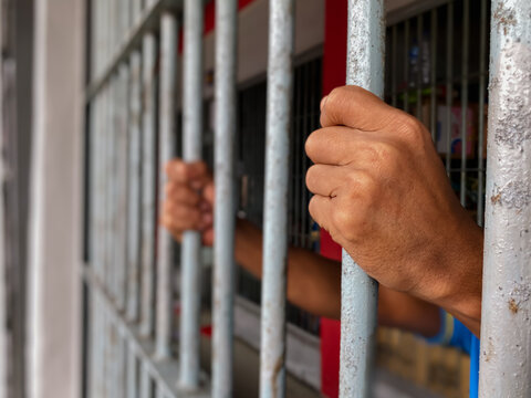 prisoner's hands behind bars	
