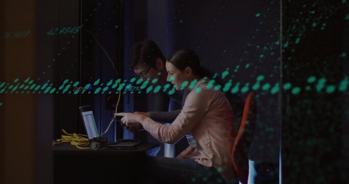 Collaborating tech staff wearing blazers connecting yellow ethernet cables at workshop, with laptop - Powered by Adobe