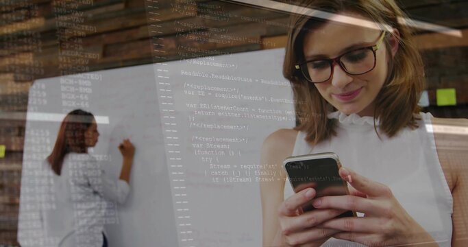Working woman in white blouse writing on whiteboard in office, viewing code overlay on smartphone