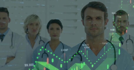 Standing male doctor in blue scrubs examining floating financial data in hospital ward, with team