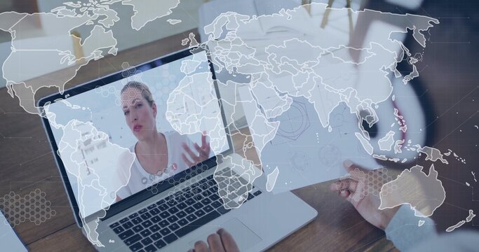 Showing white woman gesturing on laptop screen at wooden desk, with schematic and coffee mug - Powered by Adobe