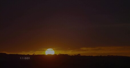 Fototapeta premium Sinking sun disc glowing over hills at rural landscape, showing silhouetted shrubs, numeric 11 001