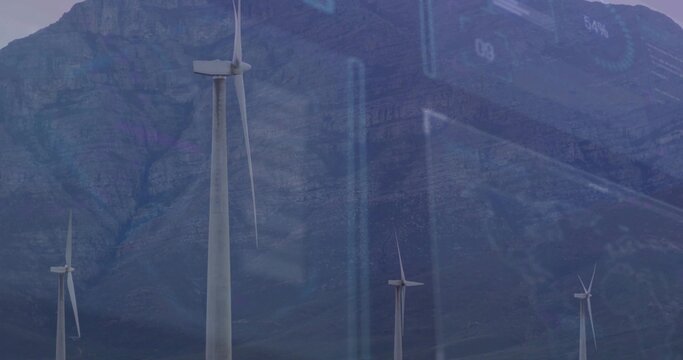 Towering large wind turbine capturing data analytics over mountain valley, with blue data overlays