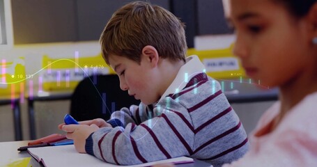 Fototapeta premium Focusing boy interacting with smartphone in classroom with notebook, pencil case and chart overlay