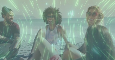 Group of four friends laughing and chatting on sandy beach, with sunglasses and pink swim shorts