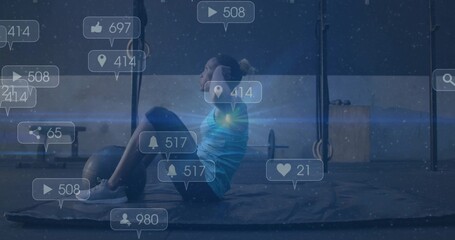 Performing woman in sportswear doing sit-ups on mat in training area, with rings and media icons