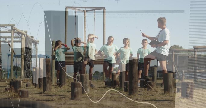 Children in green uniforms balancing on obstacle course stumps while coach pointing clipboard - Powered by Adobe