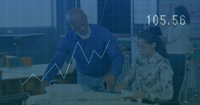 Reviewing team wearing business attire pointing and taking notes in design studio, with blueprints