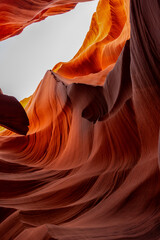 Sunlit sandstone formations inside Antelope Canyon, Arizona, glow with vibrant orange tones and layered textures, sculpted by flash floods into smooth abstract curves and intricate desert patterns