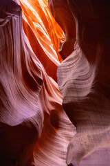 Obraz premium Flowing sandstone walls inside Antelope Canyon in Arizona, glowing with purple, pink, and orange hues, sculpted by erosion into intricate patterns and wave-like formations illuminated by desert light