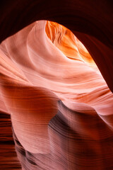 Abstract sandstone formations of Antelope Canyon, Arizona, glowing in orange and pink desert light with natural textures and curves sculpted by erosion into dramatic flowing shapes and patterns