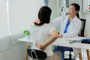 Obraz premium Asian female doctor and patient discussing spinal disc disease while sitting at table. Treatment, medical in examination room.