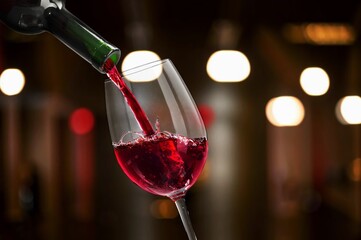 Woman pouring wine from bottle on bar background
