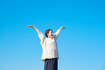 屋外で伸びをするミドルエイジの女性