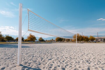 Empty sand volleyball court in a public park on a sunny day with autumn trees and mountains.