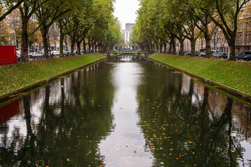 Symmetrical tree-lined canal with bridges and calm reflections