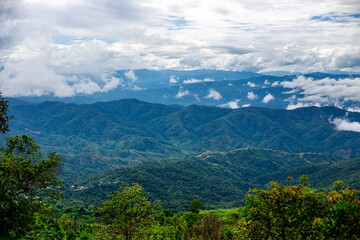 A wide-angle view of the natural scenery of the large mountains, with the wind blowing the mist and some rain falling on the trees. Happiness during the travel to study the resources.