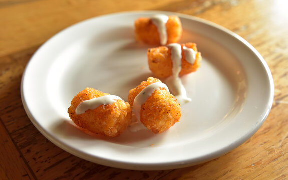 Cajun Tater Tots on a White Plate with a Drizzle orf Ranch Dressing