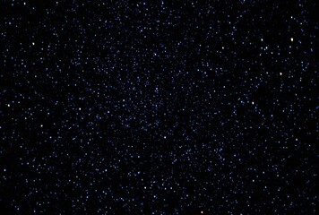 Obraz premium Dark expansive background filled with multitude of tiny, sparkling blue and white stars, suggesting a vast cosmic night sky, or a distant galaxy
