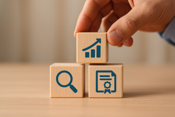 Wooden block with growth chart, magnifying glass, and certificate icons held by hand