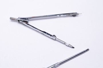 Silver Drawing Compass with Needle and Pencil Attachment on White Background, Close-Up.