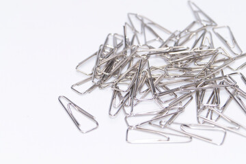 Pile of Silver Paper Clips on White Background, Office Supplies, Stationery Items, Metal Fasteners, Close-up View.