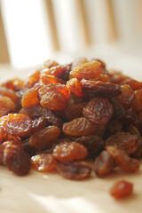 Dried grapes piled on wooden surface in bright sunlight