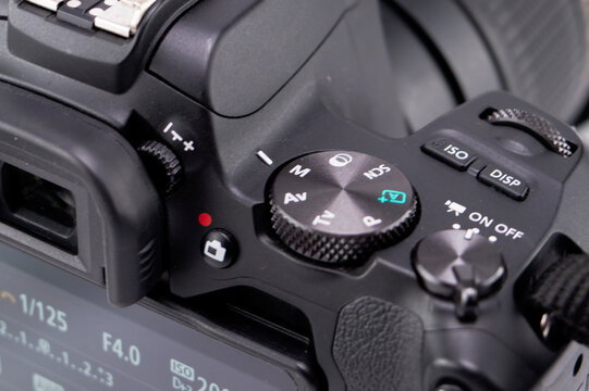 Close-up of a Black Digital Cameras Top Panel with Mode Dial and Buttons, Showing Camera Settings.