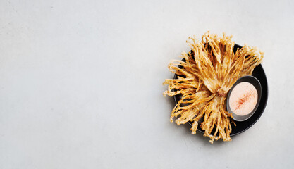 Fried Enoki Mushrooms with sauce on concrete background, top view