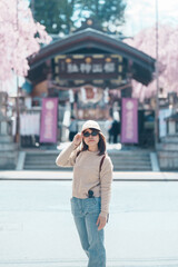 Fototapeta premium Woman tourist sightseeing Sakurayama Shrine with Cherry blossom in Spring season, happy traveler travel in Morioka city, Iwate prefecture, Japan. famous Landmark Travel and Vacation destination