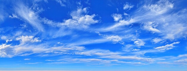 A vibrant blue sky filled with wispy, textured white cirrus clouds streaking across the frame, creating a sense of expansive openness