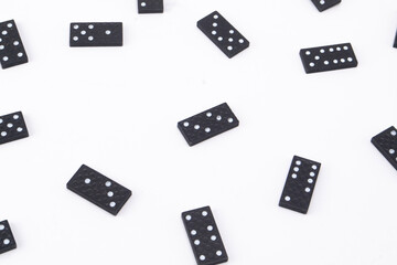 Scattered Black Domino Tiles with White Pips on a Clean White Background, Game Pieces.