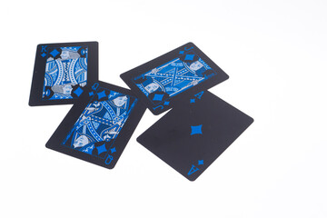 Four Black Playing Cards with Blue Designs Scattered on a White Background, Close-Up View.