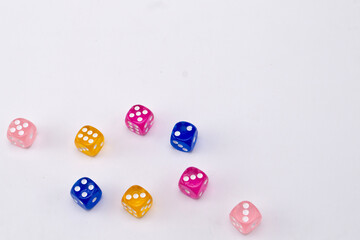 Colorful Dice Scattered on White Background, Pink, Blue, and Gold Dice with White Pips.
