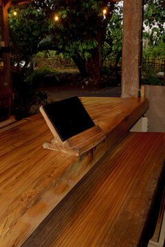 A digital tablet on a wooden counter with rustic cafe atmosphere, perfect for mockup, restaurant POS display, or technology in cozy coffee shop environment.