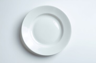 Simple, clean shot of a white, round porcelain plate on a white surface, top-down view, showcasing subtle shadow