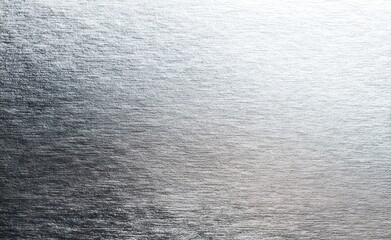 Abstract image of textured silver surface with gradient from dark to light, showing subtle horizontal lines and an overall metallic sheen