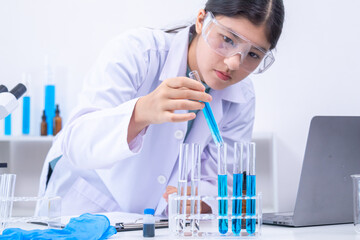 Fototapeta premium Teen scientist girl conducting science test by carefully evaluating blue solution in laboratory. Science, laboratory, experiment, and research demonstrate academic progress and practical skills.