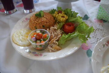 Indonesian fried rice with spices such as onions, chilies, and tomatoes, with various garnishes such as cucumber