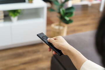 Elderly woman Watching smart TV and using remote controller Hand holding television audio remote control Middle age Asian woman movie Television series spending time at home