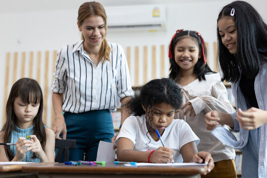 Diverse group of elementary school students working together on a classroom activity, with a teacher supervising. Represents teamwork, education, creativity, and inclusive learning environment.