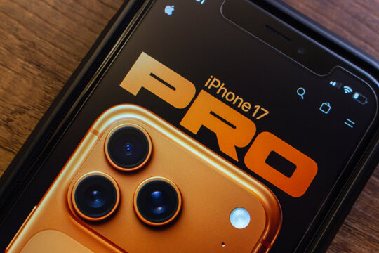 Mexico City, MEXICO - Sep 9 2025 : Close-up of smartphone showing iPhone 17 Pro promotional page with bold text and gold model camera detail, on wooden surface.
